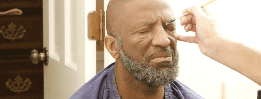 Man getting makeup applied with brush.